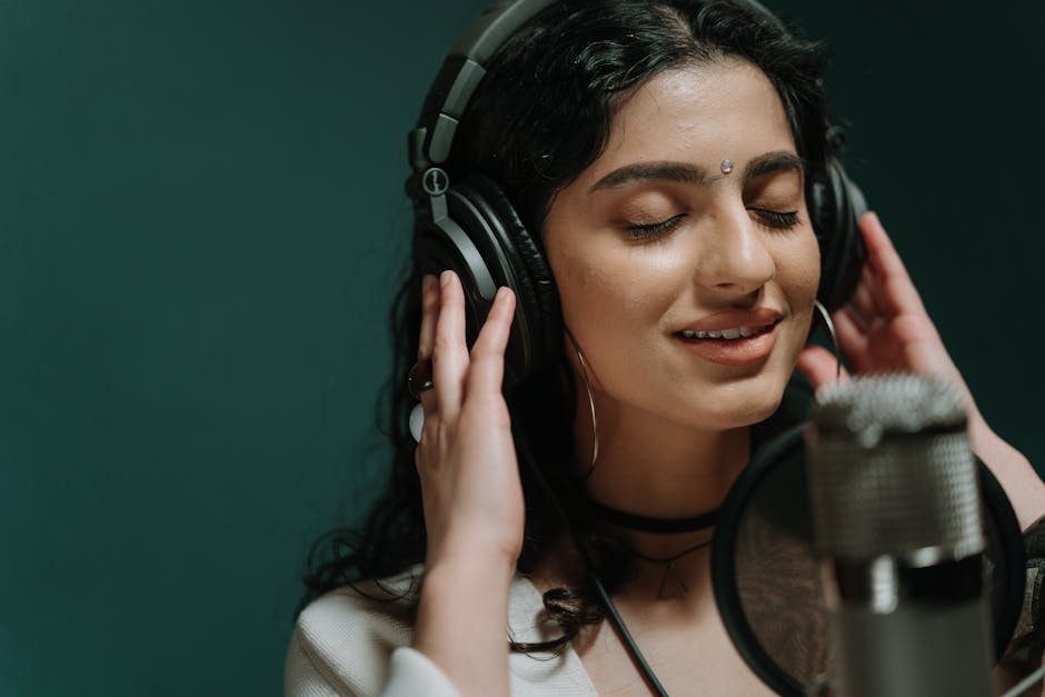 A woman is recording music in a professional studio with headphones and microphone.