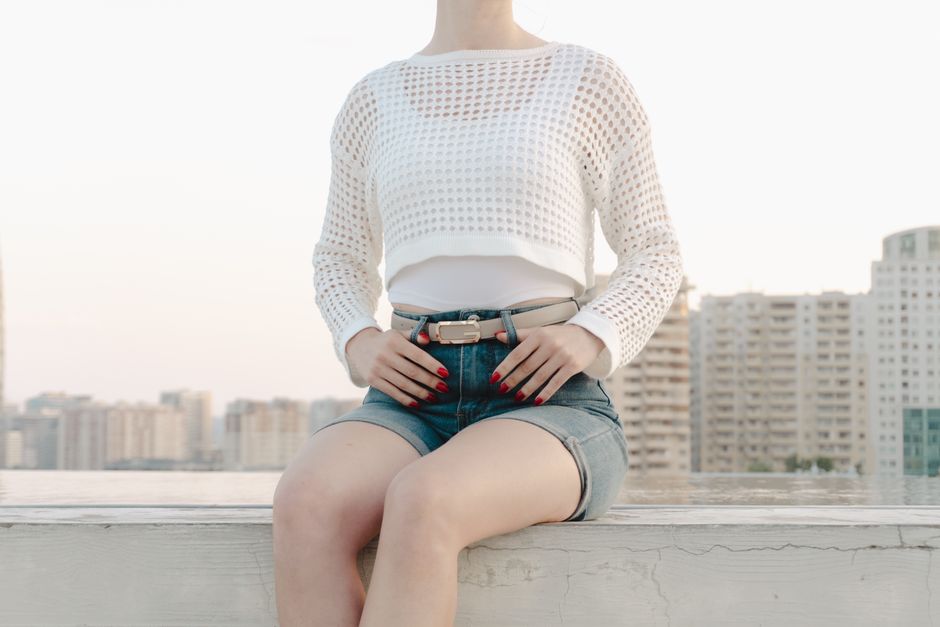 Stylish woman in urban setting, wearing summer fashion with a cityscape backdrop.