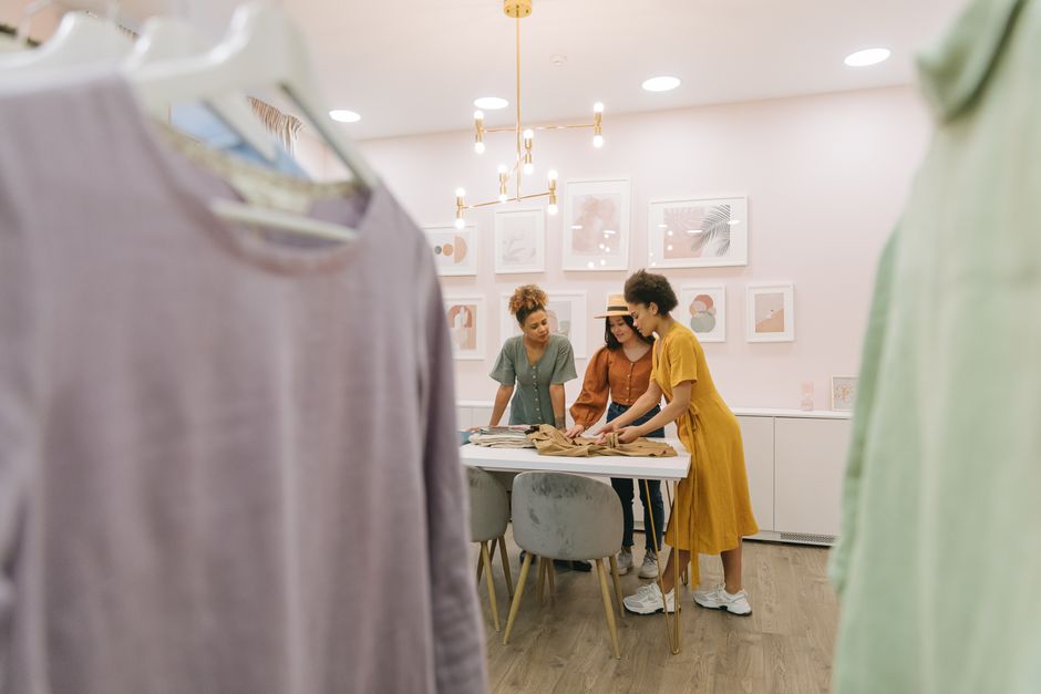 African American and Asian women working on design in modern fashion studio.