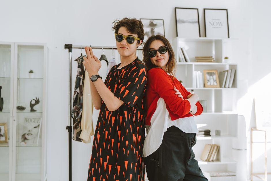 Stylish young models posing back-to-back indoors, embracing modern fashion trends.