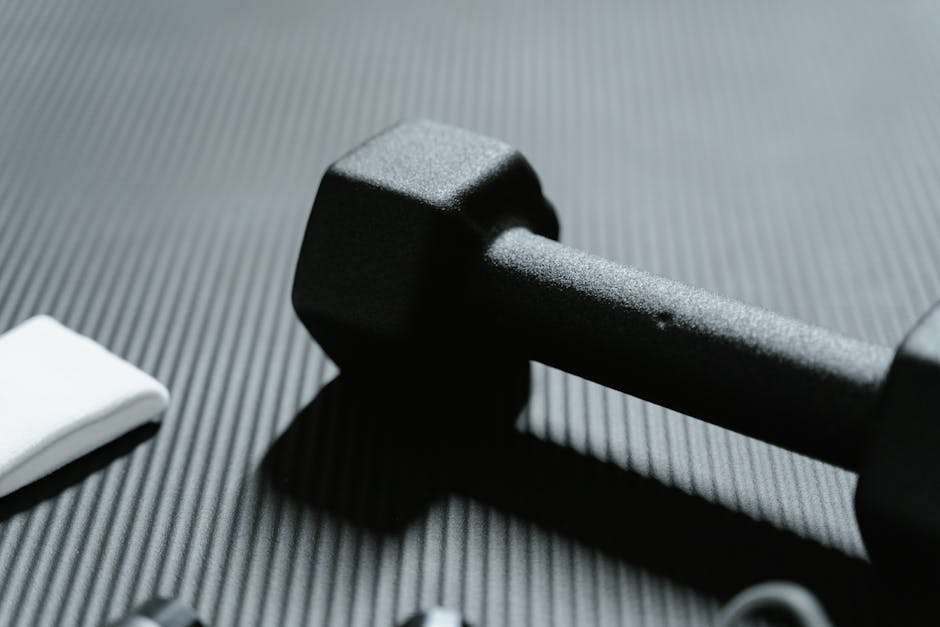 Detailed view of a black dumbbell on textured mat for fitness workout