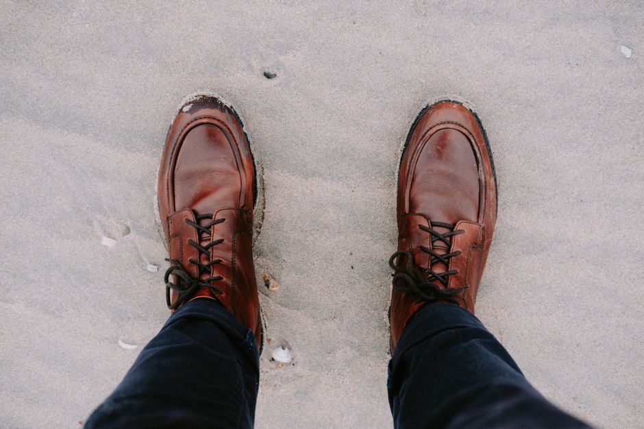 Stylish brown leather boots on a sandy beach, perfect for a fall fashion look.