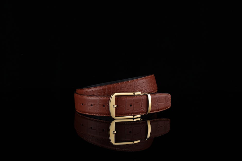 Stylish brown leather belt with a gold buckle on black background.