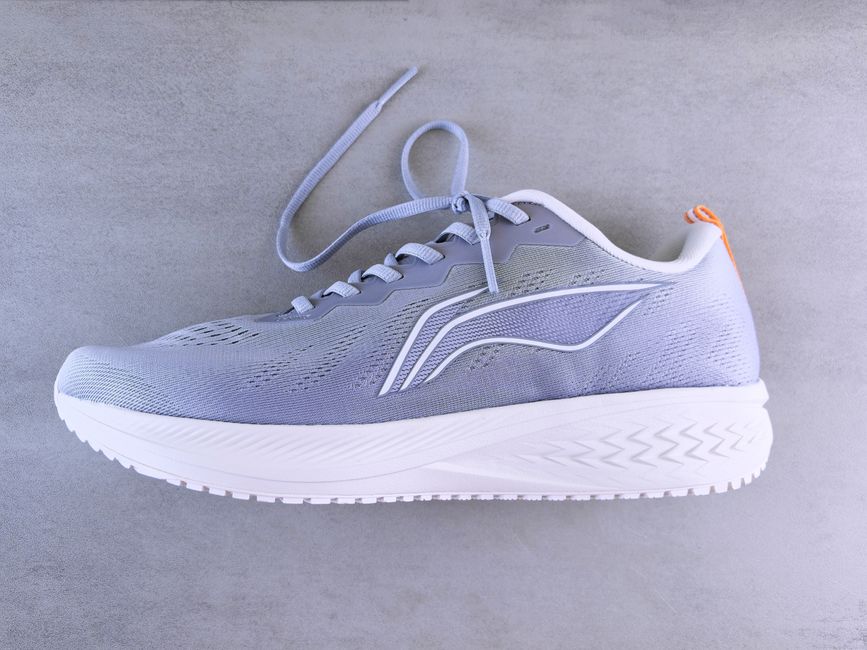 A modern grey sports shoe displayed on a textured surface, perfect for fashion and lifestyle themes.