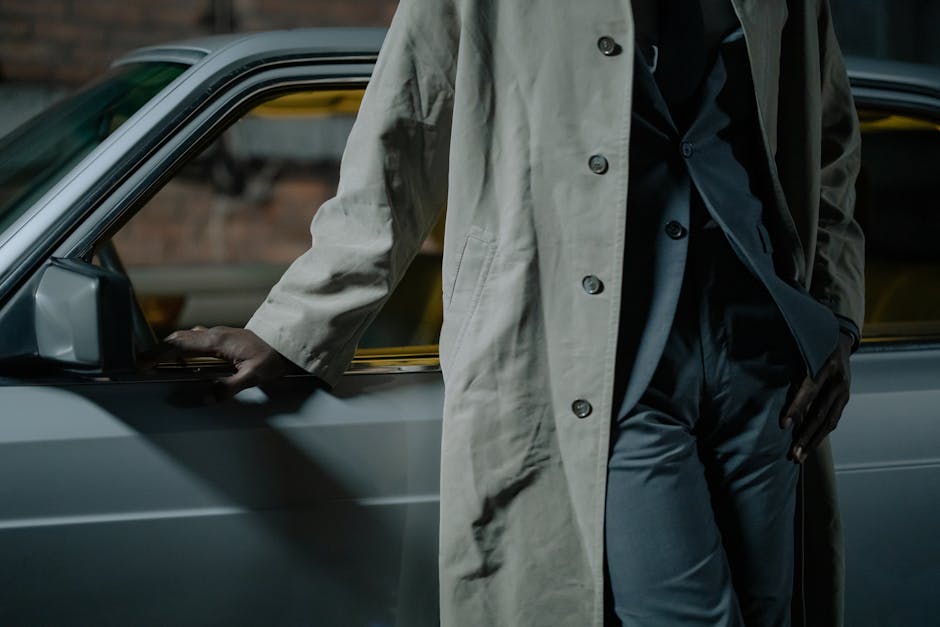 Mysterious figure in trench coat leans against a vintage car, evoking a noir detective vibe.