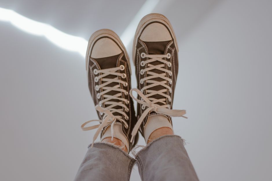 Pair of casual sneakers worn with jeans, suggesting a laid-back vibe.