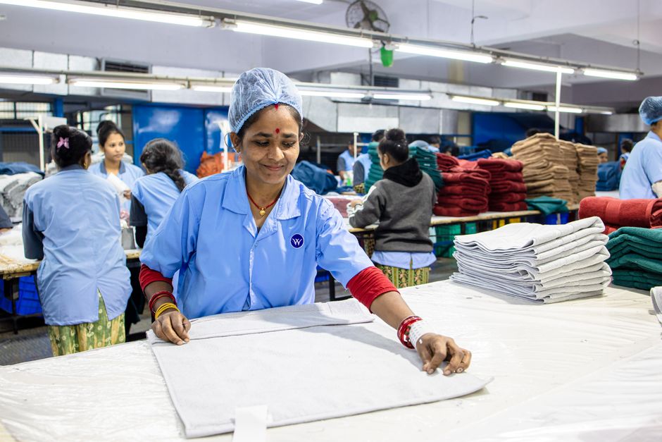 Indian textile workers sorting fabrics in a busy factory setting.