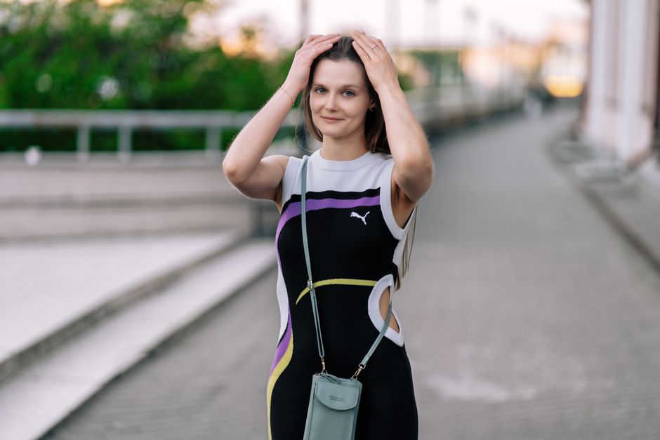 Confident woman in a fashionable dress posing on an urban street, showcasing modern style and elegance.