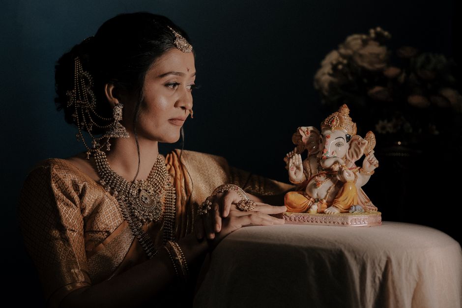 A woman in traditional Indian attire admires a Ganesha idol, highlighting cultural reverence.