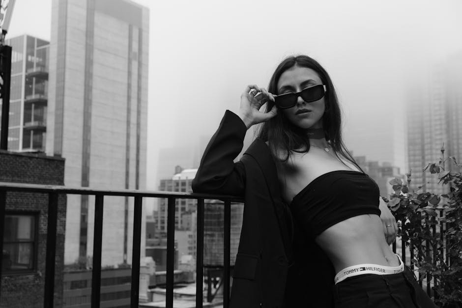 Chic black and white photo of a fashionable woman posing on a rooftop.
