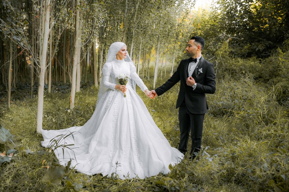 Bride and groom in elegant attire posing in a serene forest setting.
